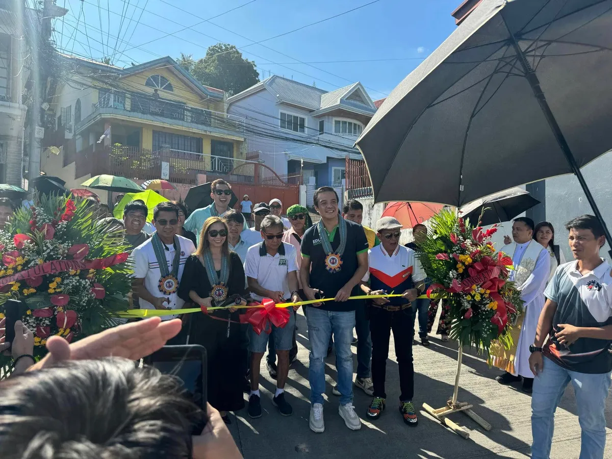A ribbon-cutting ceremony marking a completed project, attended by local officials, clergy and residents.